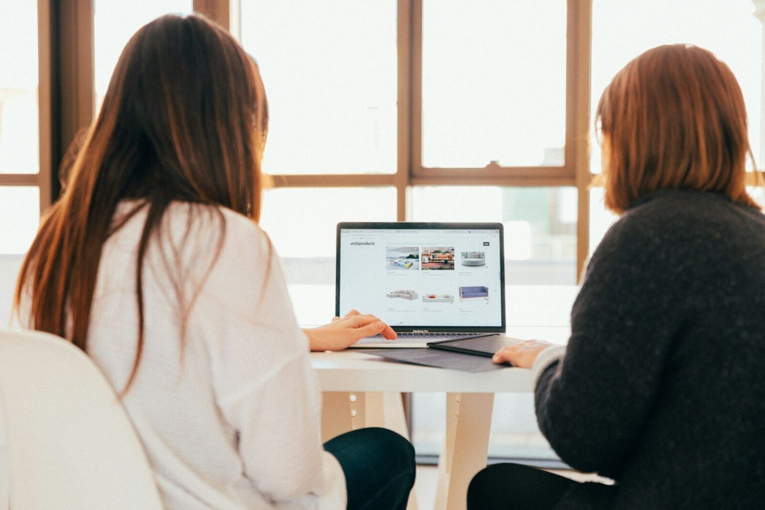 Jeden duży klient może być największym sukcesem i największym zagrożeniem firmy two women talking while looking at laptop computer